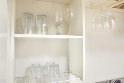 a white cabinet filled with glass wine glasses at Shirogane Apartment in Tokyo