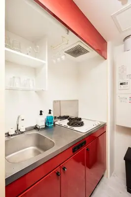a kitchen with red cabinets and a sink at Shirogane Apartment in Tokyo