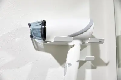 a white toilet with a brush on the wall at Shirogane Apartment in Tokyo