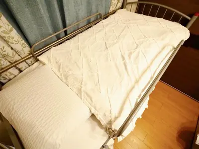 a metal bed with a white sheet on it at 302Near Ueno Heart of city in Tokyo