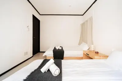 a bedroom with two beds with white sheets at GJbb \u5c0f\u5ca9\u99c5\u304b\u3089\u5f92\u6b696\u5206 \u7fbd\u7530\u7a7a\u6e2f\u6210\u7530\u7a7a\u6e2f\u884c\u304d\u306e\u76f4\u884c\u30d0\u30b9 \u5b50\u9023\u308c in Tokyo