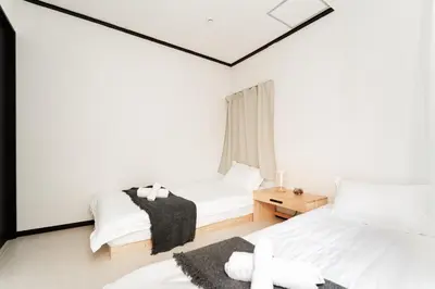 a white bedroom with two beds and a window at GJbb \u5c0f\u5ca9\u99c5\u304b\u3089\u5f92\u6b696\u5206 \u7fbd\u7530\u7a7a\u6e2f\u6210\u7530\u7a7a\u6e2f\u884c\u304d\u306e\u76f4\u884c\u30d0\u30b9 \u5b50\u9023\u308c in Tokyo