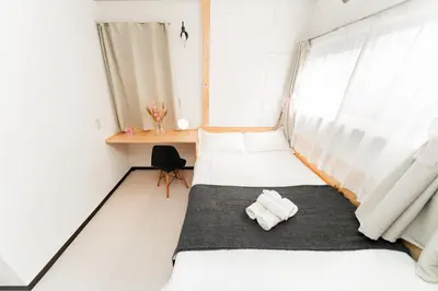 two beds in a room with a desk and window at GJbb \u5c0f\u5ca9\u99c5\u304b\u3089\u5f92\u6b696\u5206 \u7fbd\u7530\u7a7a\u6e2f\u6210\u7530\u7a7a\u6e2f\u884c\u304d\u306e\u76f4\u884c\u30d0\u30b9 \u5b50\u9023\u308c in Tokyo