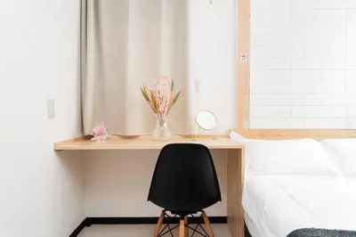 a desk with a black chair next to a bed at GJbb \u5c0f\u5ca9\u99c5\u304b\u3089\u5f92\u6b696\u5206 \u7fbd\u7530\u7a7a\u6e2f\u6210\u7530\u7a7a\u6e2f\u884c\u304d\u306e\u76f4\u884c\u30d0\u30b9 \u5b50\u9023\u308c in Tokyo