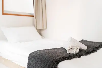 a bed with a blanket and a towel on it at GJbb \u5c0f\u5ca9\u99c5\u304b\u3089\u5f92\u6b696\u5206 \u7fbd\u7530\u7a7a\u6e2f\u6210\u7530\u7a7a\u6e2f\u884c\u304d\u306e\u76f4\u884c\u30d0\u30b9 \u5b50\u9023\u308c in Tokyo