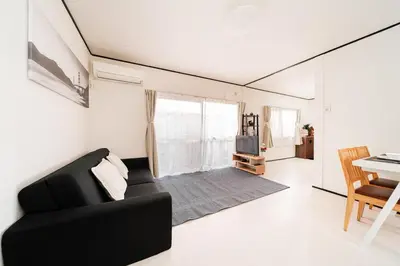 a living room with a black couch and a table at GJbb \u5c0f\u5ca9\u99c5\u304b\u3089\u5f92\u6b696\u5206 \u7fbd\u7530\u7a7a\u6e2f\u6210\u7530\u7a7a\u6e2f\u884c\u304d\u306e\u76f4\u884c\u30d0\u30b9 \u5b50\u9023\u308c in Tokyo