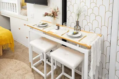 a white kitchen with a table and stools at Coco Aoto in Tokyo