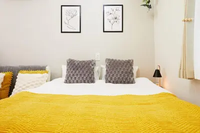 a bedroom with a bed with a yellow blanket at Coco Aoto in Tokyo