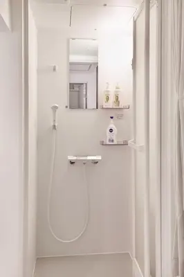 a white bathroom with a shower and a mirror at Coco Aoto in Tokyo