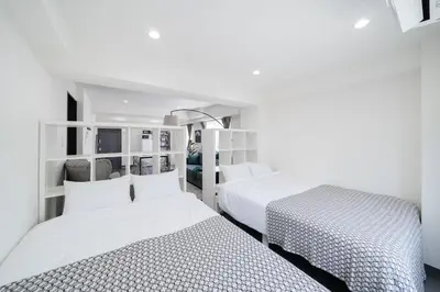 two beds in a room with white walls at K'shotel Takadanobaba 山手線駅6分繁華街に近い静かな住宅街のデザイナーズホテル in Tokyo