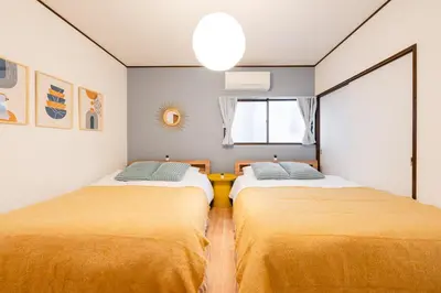 two beds in a room with yellow sheets at tai\u4e0a\u5317\u6ca24\u4e01\u76ee in Tokyo