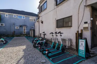 a row of scooters parked next to a building at tai\u4e0a\u5317\u6ca24\u4e01\u76ee in Tokyo