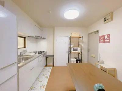 a kitchen with a wooden table and a white refrigerator at Sakura Stay \u62bc\u4e0a in Tokyo
