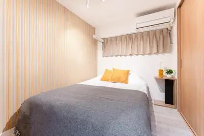 a bedroom with a bed with a gray blanket at tai\u4e21\u56fd4\u4e01\u76eeGLV\u516c\u9928701 in Tokyo