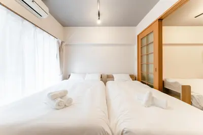 two beds in a room with white sheets at shibuya e adress in Tokyo