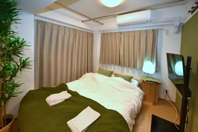 a bedroom with a large bed with green and white sheets at Karawaru Stay \u5e73\u4e95 A in Tokyo