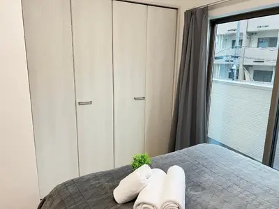 a bedroom with two towels on a bed with a window at Ikebukuro Area 2F3 KamiikeApartment in Tokyo