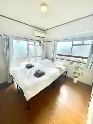 a bedroom with a bed with white sheets and a window at \u9daf\u8c37 3\u5bdd\u5ba44\u30d9\u30c3\u30c9 \u6700\u4e0a\u968e \u9daf\u8c37\u99c5\u5f92\u6b692\u5206 \u6d45\u8349\u4e0a\u91ce\u79cb\u8449\u539f\u30a8\u30ea\u30a2 in Tokyo