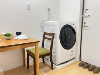 a washing machine sitting next to a table with a chair at Ikebukuro Area 2 Units 1112 KamiikeApartment in Tokyo