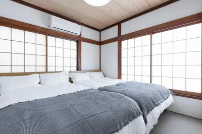 a bedroom with a bed with white sheets and windows at Direct bus from Haneda 3BR House Near Station in Tokyo