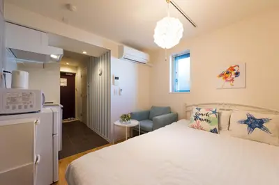 a small bedroom with a bed and a kitchen at Fare Metallo Tokyo Nakano 11-room Hotel in Tokyo