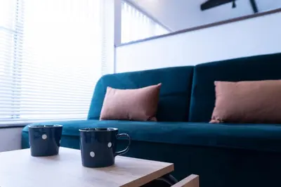 two coffee cups on a table in front of a blue couch at Skytree-House\u4eac\u5cf6 in Tokyo