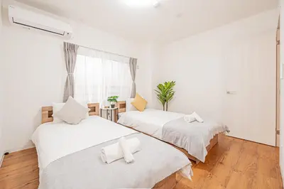 two beds in a room with white walls and wood floors at Mori house \u6839\u5cb8 401 in Tokyo