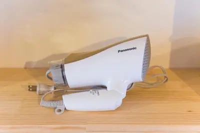a white hair dryer sitting on a wooden table at Azur Shibuya -Apartment House- in Tokyo