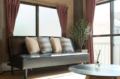 a leather couch in a living room with windows at Comfort Stay \u4e2d\u91ce in Tokyo