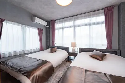 two beds sitting in a room with windows at Comfort Stay \u4e2d\u91ce in Tokyo