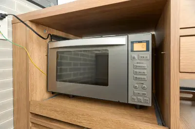 a microwave oven in a wooden cabinet at Comfort Stay \u4e2d\u91ce in Tokyo