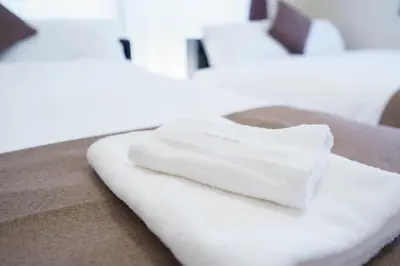 a white towel sitting on the edge of a bed at Laputa \u6c60\u888b in Tokyo
