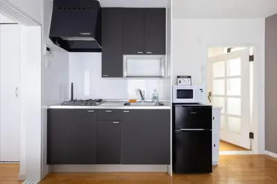 a kitchen with black cabinets and a sink and a microwave at Laputa \u6c60\u888b in Tokyo