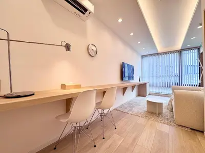 a room with a desk with chairs and a clock on the wall at POINT Apartment Hotel - Ueno - Asakusa - Iriya in Tokyo