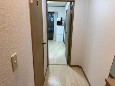 a hallway with a door leading to a kitchen with a refrigerator at Ikebukuro Area 1F01 AbanNishiikeApartment in Tokyo