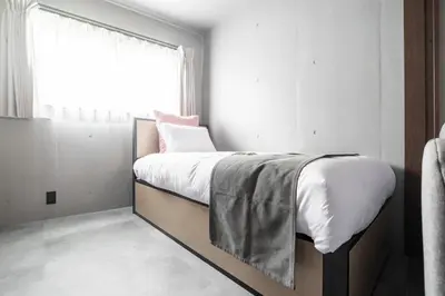 a bedroom with a bed with white sheets and a window at VALUE MAISON kagurazaka in Tokyo