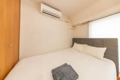 a bedroom with a white bed with a book on it at JR Kamata Station is a 3-minute walk, Shinagawa is 7 minutes by train, and Keikyu Kamata Station has direct access to Haneda Airport, Tokyo, Shinagawa, Yokohama, and Ueno in Tokyo
