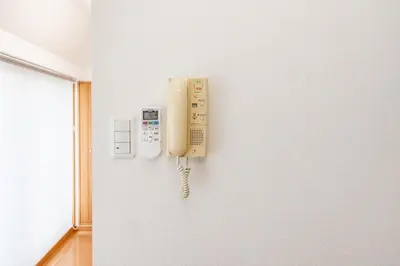 a phone is hanging on a wall at JR Kamata Station is a 3-minute walk, Shinagawa is 7 minutes by train, and Keikyu Kamata Station has direct access to Haneda Airport, Tokyo, Shinagawa, Yokohama, and Ueno in Tokyo