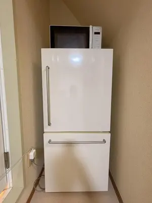 a white refrigerator with a microwave on top of it at Mori House \u6e0b\u8c37\u672c\u753a in Tokyo