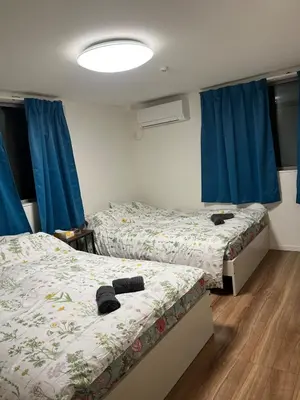 two beds in a room with blue curtains at Direct access to Shinjuku 1 station, atrium living room, super large entrance in Tokyo
