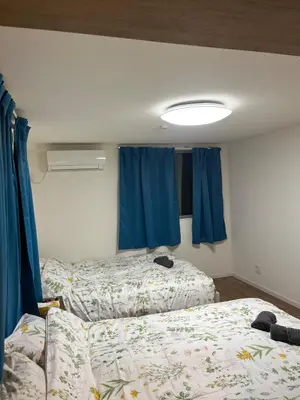 two beds in a room with blue curtains at Direct access to Shinjuku 1 station, atrium living room, super large entrance in Tokyo