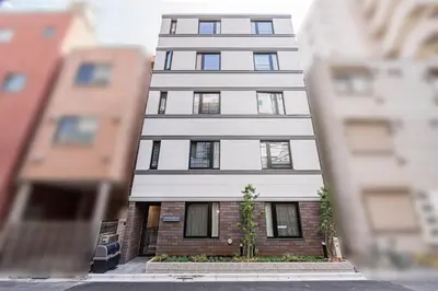 a tall apartment building in the middle of a street at ZAITO-Terra hotel \u65b0\u5fa1\u5f92\u753a\u99c5\u5f92\u6b69\u4e09\u5206 in Tokyo