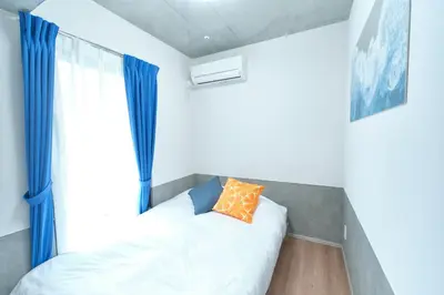 a bedroom with a bed and a window with blue curtains at J-ARC Shinjuku by Tranova in Tokyo