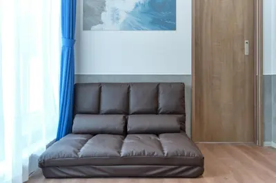 a brown leather couch in a room with blue curtains at J-ARC Shinjuku by Tranova in Tokyo