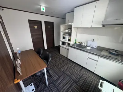 a small kitchen with a wooden table and white cabinets at Sun flower Guest house in Tokyo