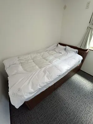 a bedroom with a bed with white sheets and a window at Sun flower Guest house in Tokyo