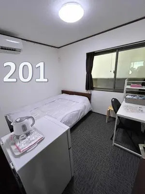 a small room with a bed and a desk and a table with a table at Sun flower Guest house in Tokyo