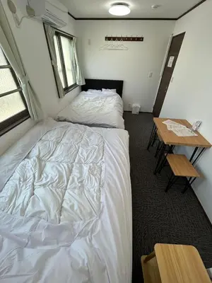 a bedroom with a white bed and a table at Sun flower Guest house in Tokyo