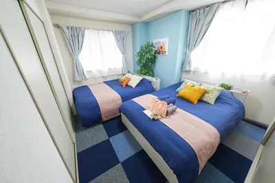 two beds in a room with blue walls at Shamrock Aoto 101 Cozy Tokyo Stay Near Station Airport Disney Access in Tokyo