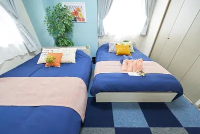 two twin beds in a room with blue walls at Shamrock Aoto 101 Cozy Tokyo Stay Near Station Airport Disney Access in Tokyo